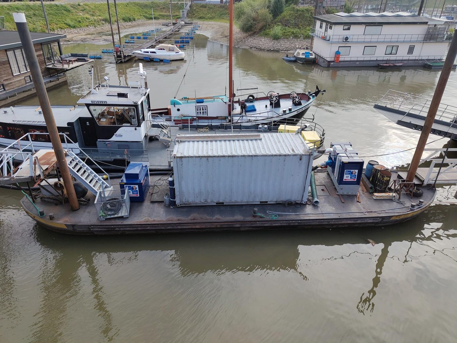 Pompsets van Archy Rental op een ponton in een haven, met een container ertussen